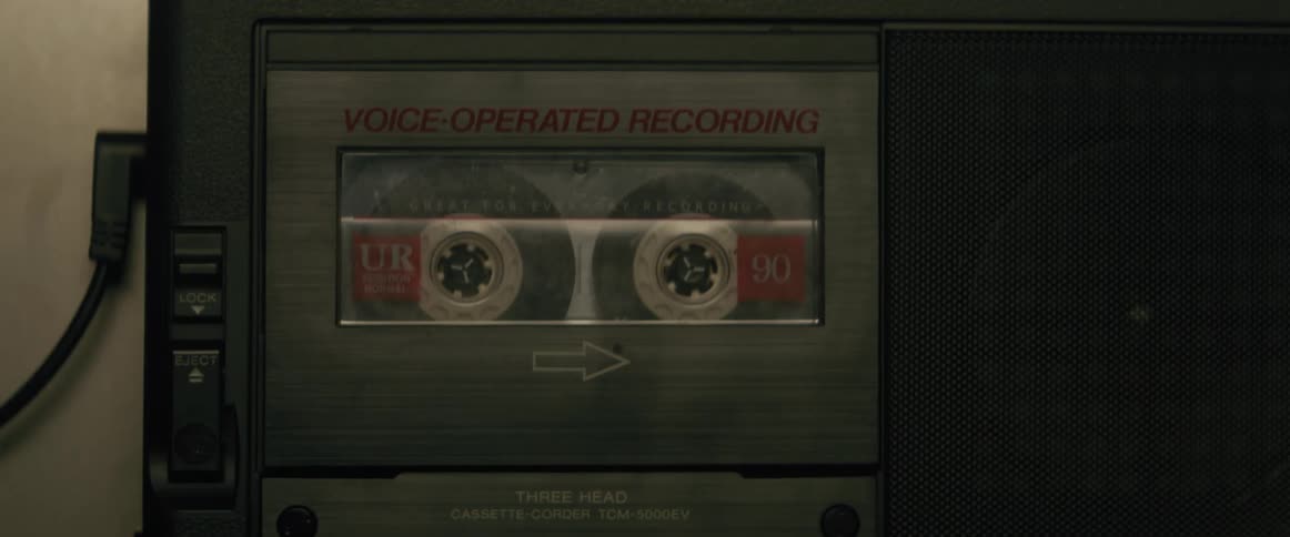 A hand placing a vintage cassette tape inside a player