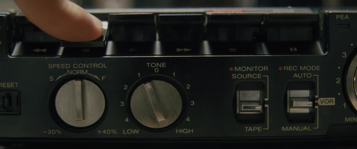 A persons finger pressing a button on an old electronic device with various texts above the buttons