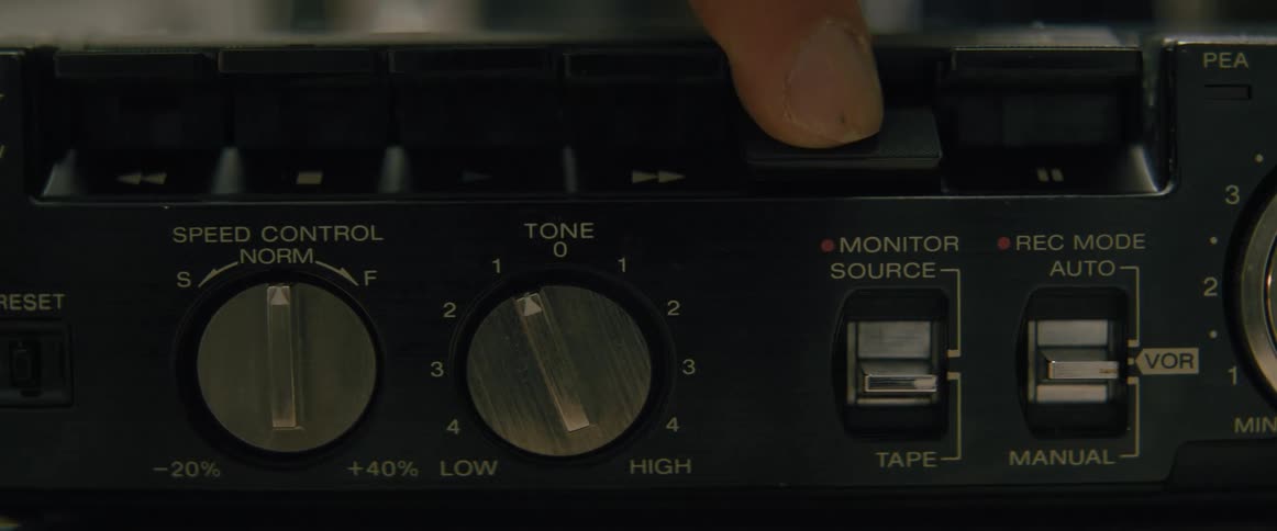 A hand presses the record button on a retro cassette tape player