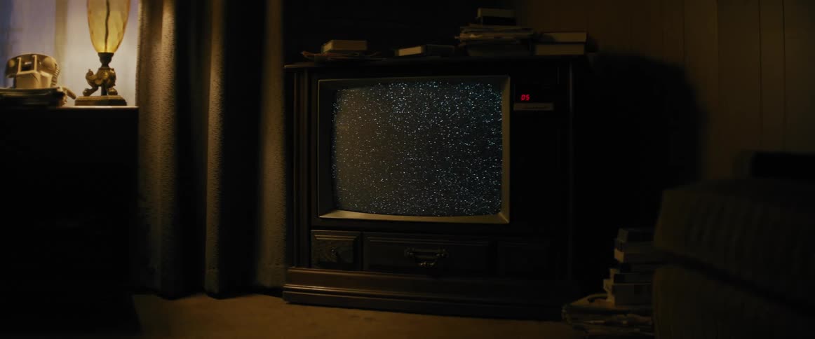 Old style console television displays signal static in a dimly lit room