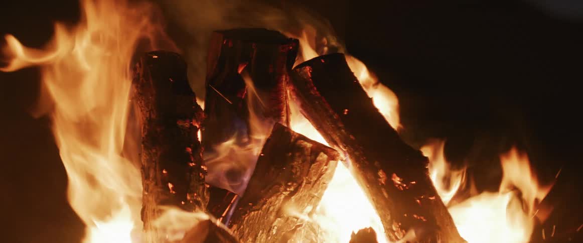 Sparks leap off of a raging nighttime bonfire