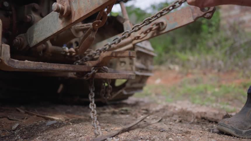 A man attaches a chain to a tractor