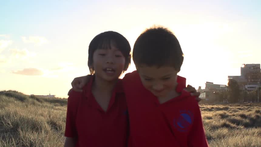 The sun shines on two boys as they walk through a field
