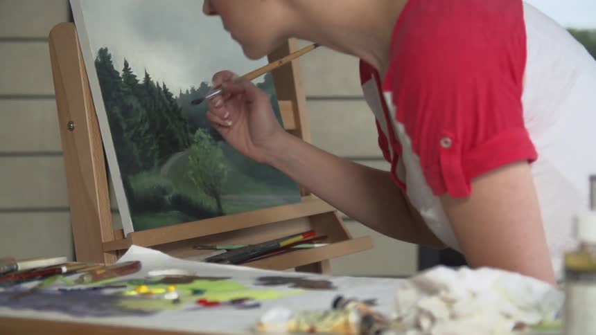 A short-haired woman painting a landscape on canvas