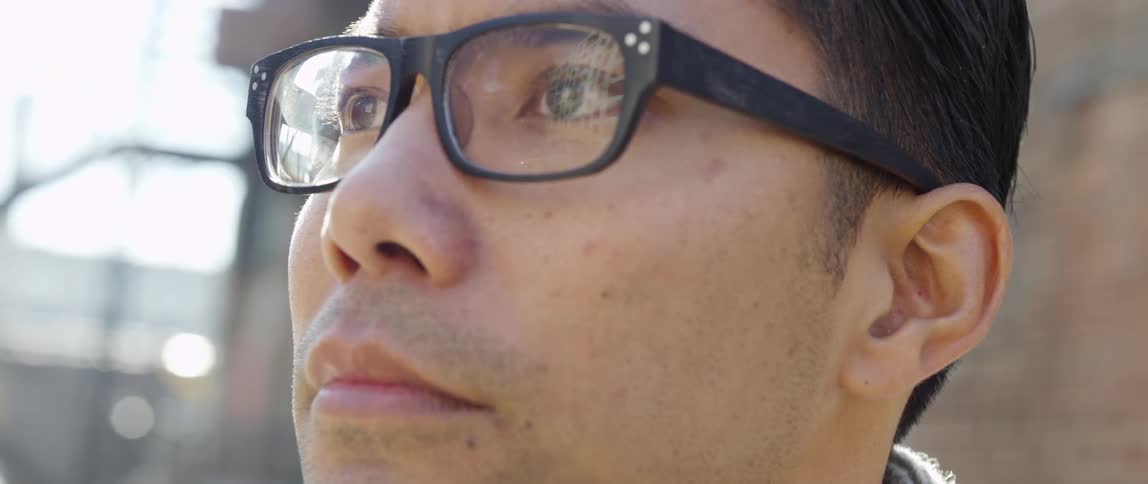 A man wearing glasses stares into the distance