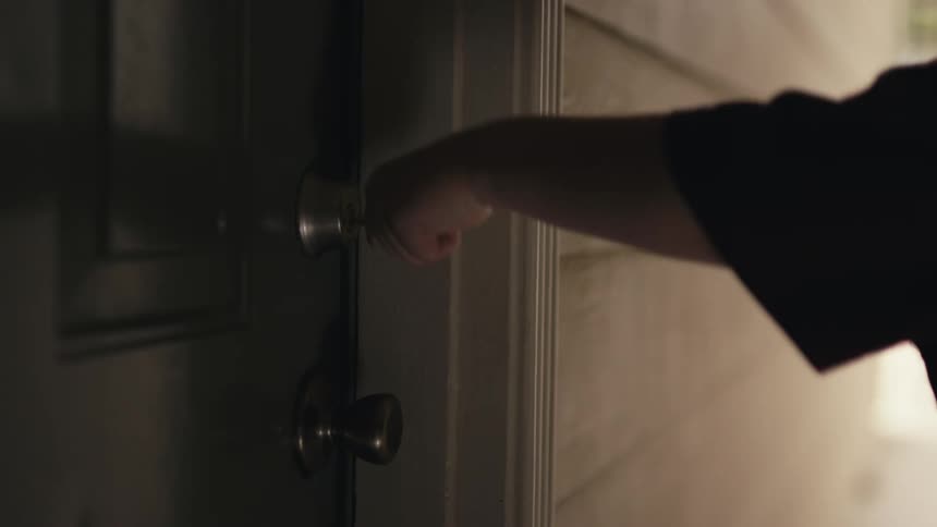 A persons arm putting a key into a door lock and locking it