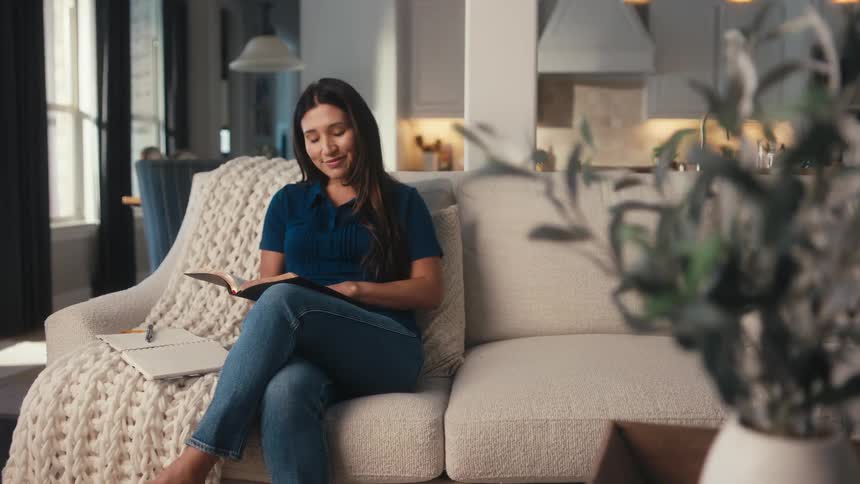 Woman sitting on the couch in the living room reading a book