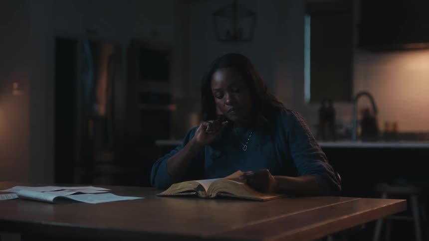 Woman sitting at table reading a bible
