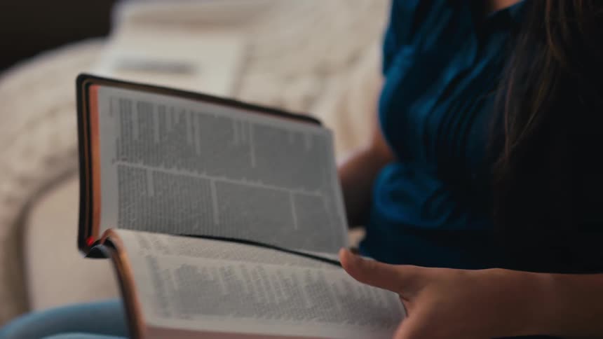 Women sits on her living room couch to read from the bible