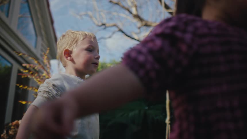 A couple of children play with water balloons in the backyard