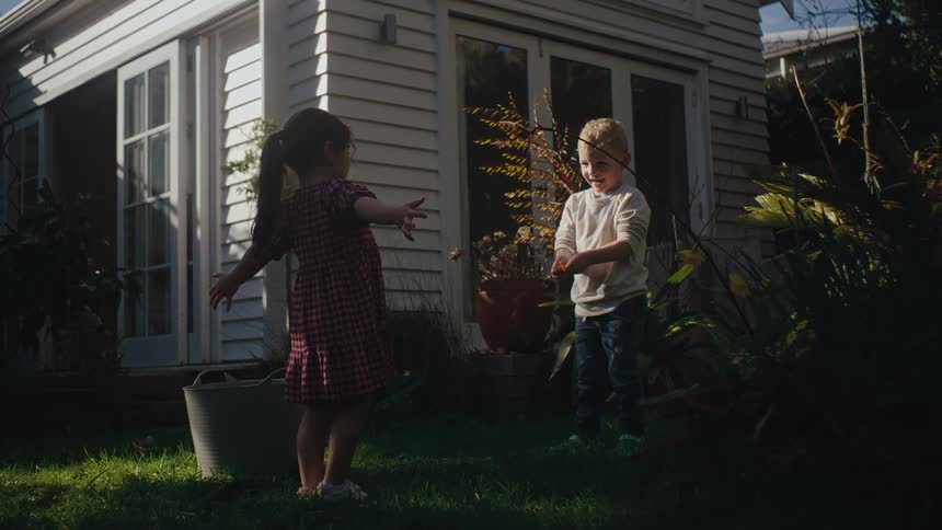 Two children in the backyard of a house playing