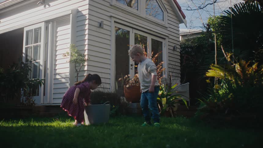Two small children in the backyard playing with water balls