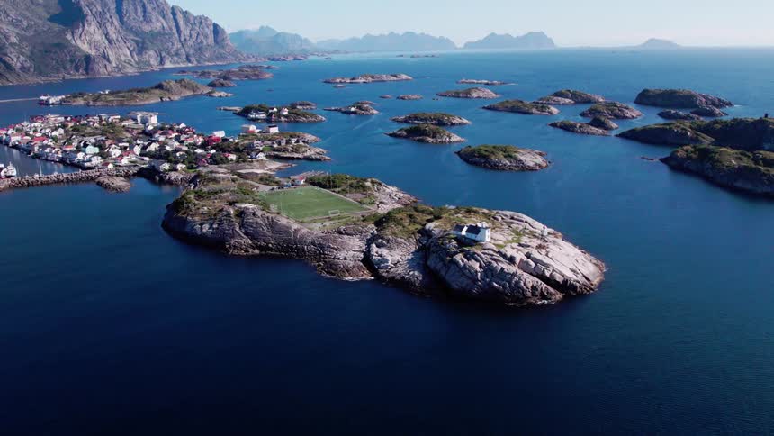 Aerial landscape of an island with a football field and an urban city surrounded by the sea and the coast