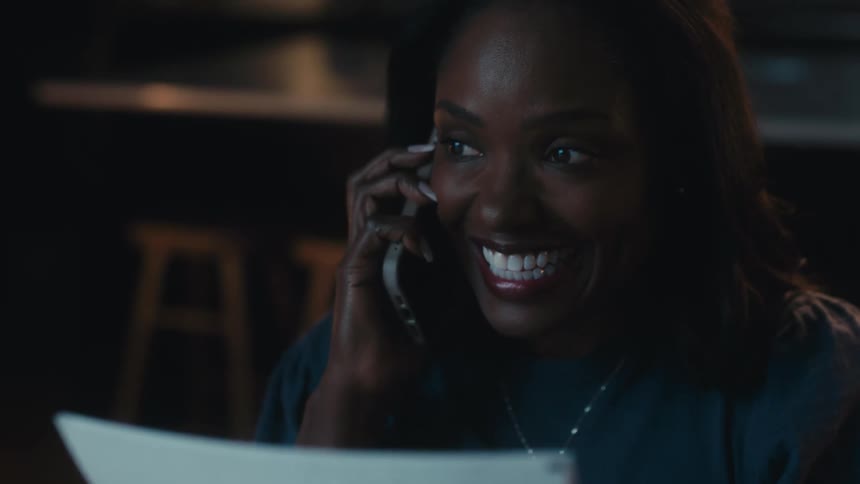 Woman sitting at home receives good news and makes a call to share it