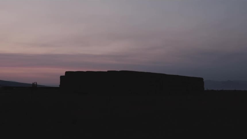 Silhouette of a building in a field with the sky in shades of purple on a morning