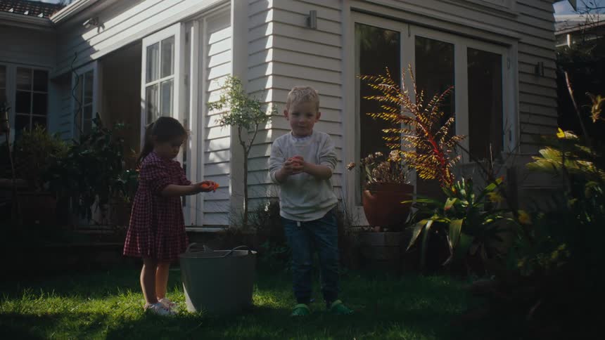 Young boy and girl playing with water balls in the backyard of a house