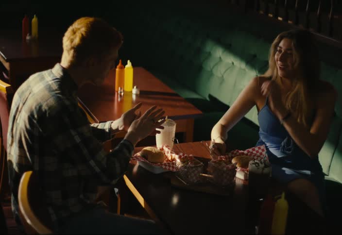 A man and woman smile and talk while eating together in a restaurant