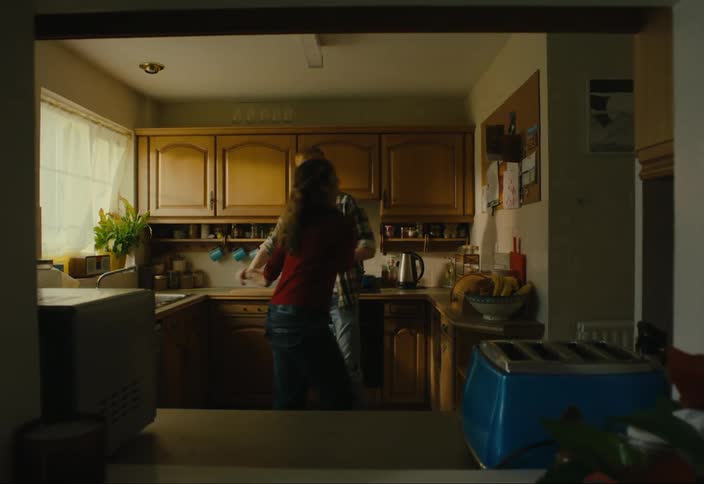 A couple of a man and a woman dancing in a kitchen where there are two more people then they leave
