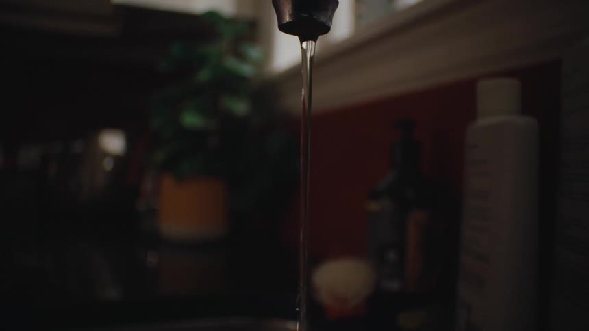 Childs hand holding a toothbrush and wetting it under the tap