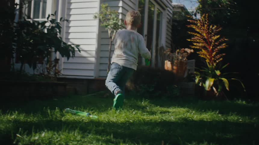 Small children in a garden playing with a water gun
