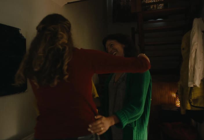 Older female relatives welcome younger woman to their home happily while man stands nearby