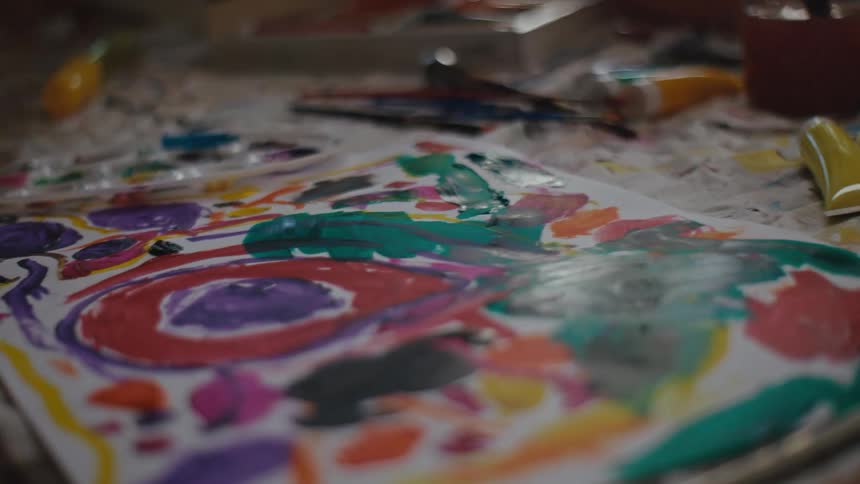 A child is painting with a brush on paper