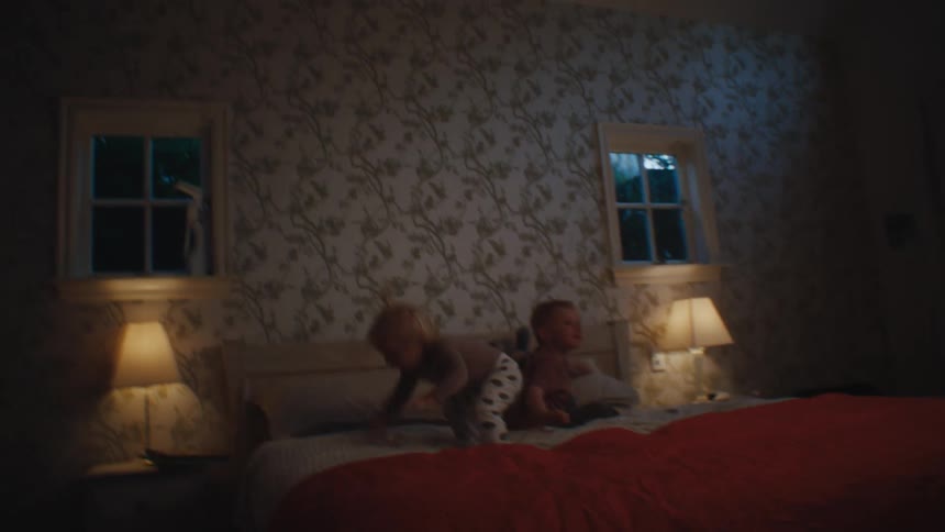 Two small children play on the bed in a bedroom