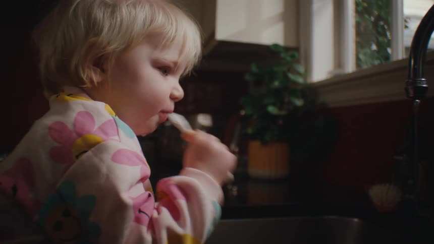 Little girl wetting her toothbrush in the sink with the water tap running