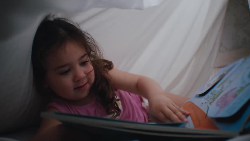 Little girl under the covers reading a book