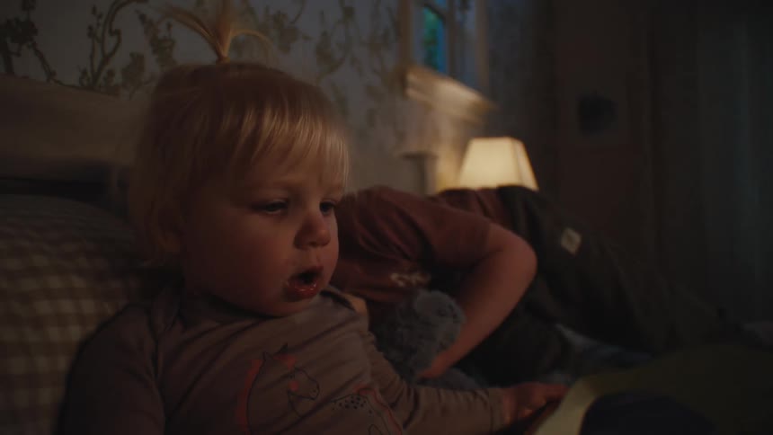Two small children sitting on a bed in a bedroom playing