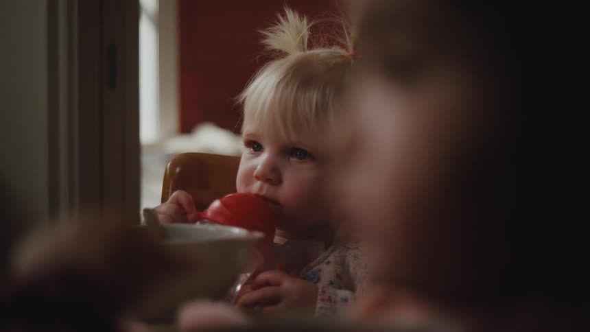 Two small children sitting at the table eating and drinking