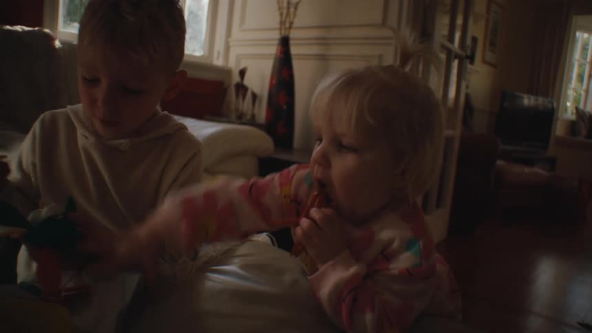 Two small children in the living room playing and interacting with toys