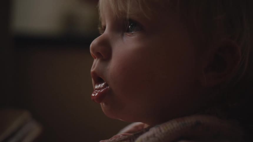 Side portrait of a little blonde girl with her mouth open