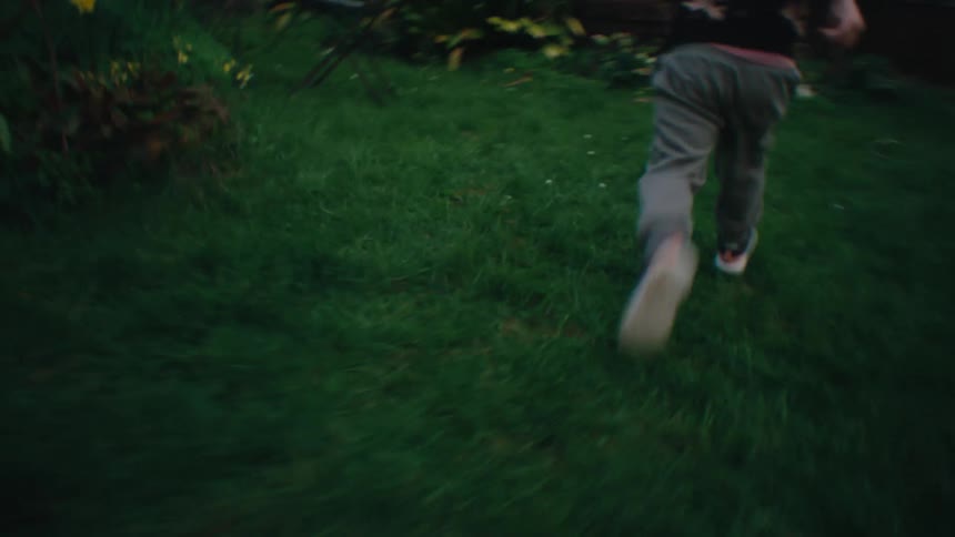 Little blond boy running in a grassy yard