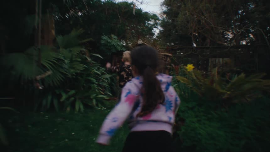 A couple of children running on the green grass in the backyard