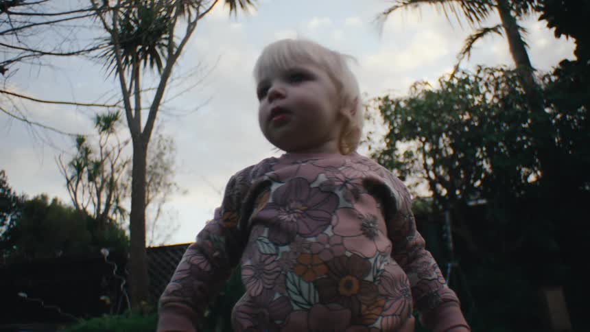 Little blonde child playing in the backyard with grass
