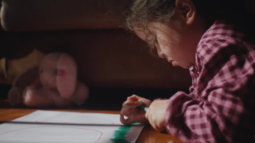 Girl lying on the floor trying to take the cap off a pen