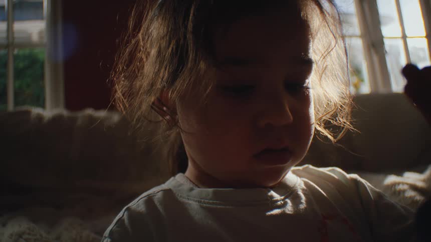 Closeup of a toddlers face sitting in a dimly lit living room