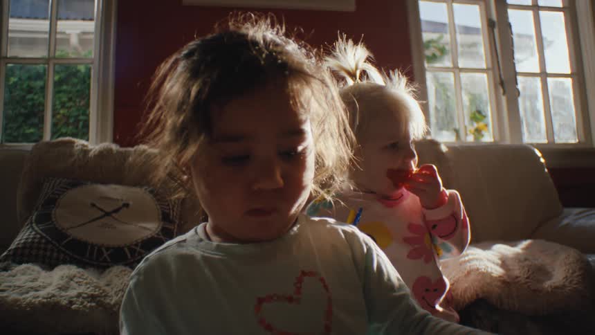 Three small children in the living room interacting and playing with toys