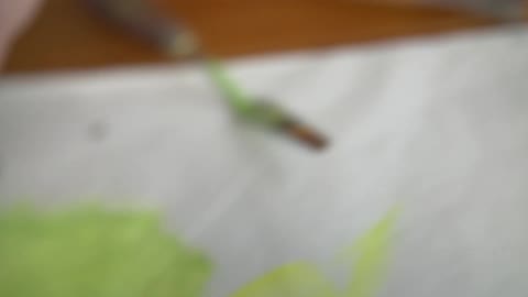 A woman opens a tube of yellow paint and squeezes some out