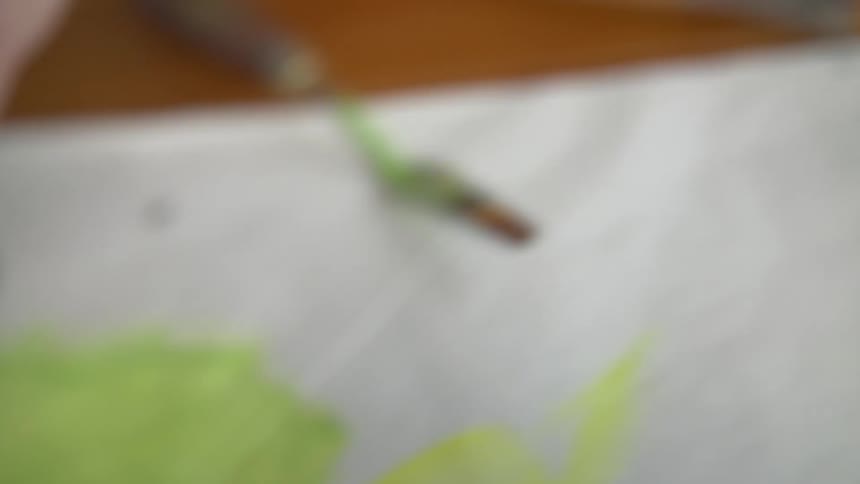 A woman opens a tube of yellow paint and squeezes some out