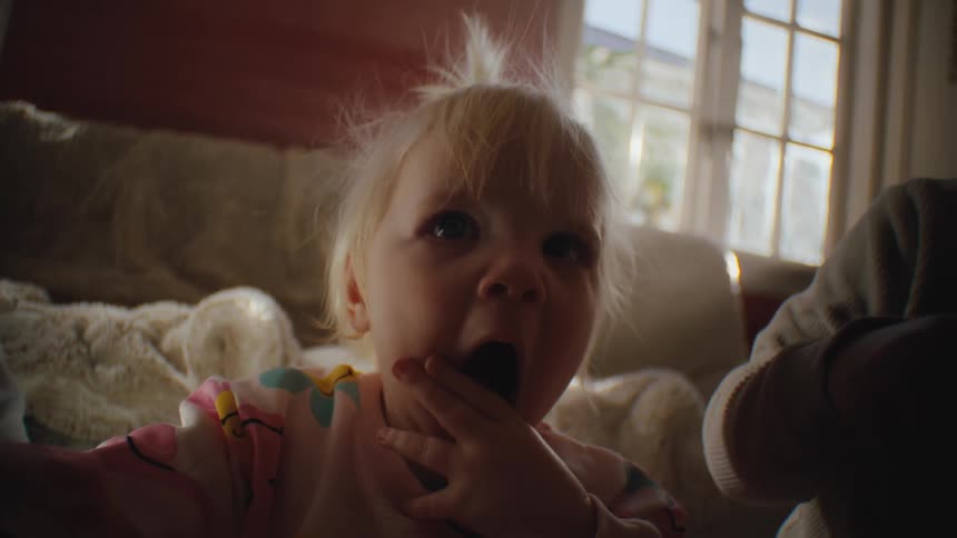 Portrait of a little blonde girl with her hand over her mouth