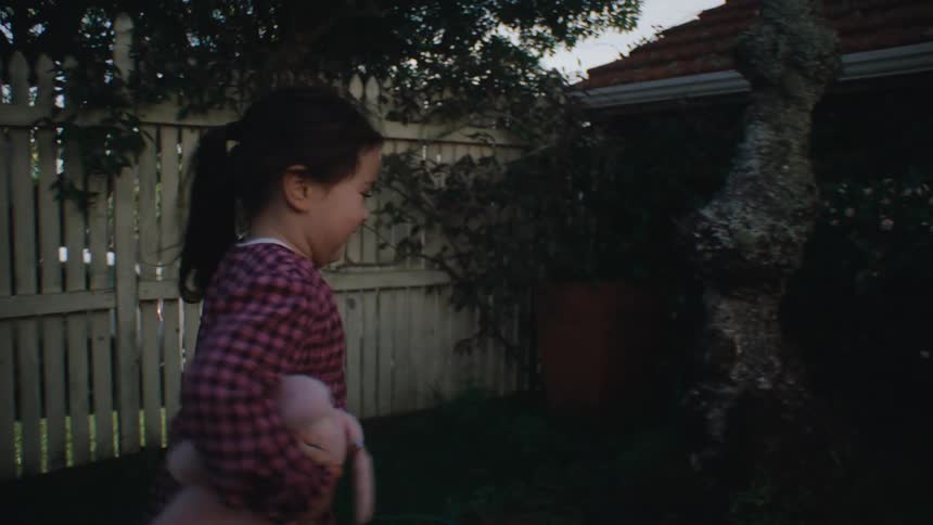 Little girl running in the backyard of a house