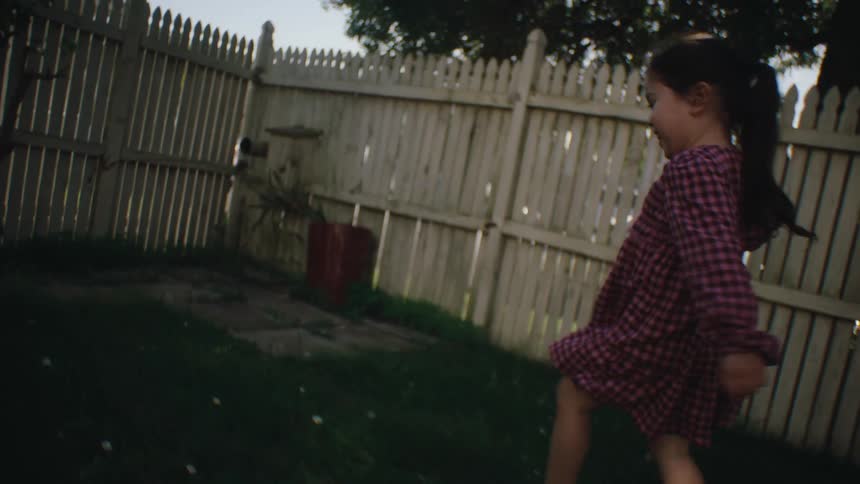 Girl running through the grass in the backyard of a house