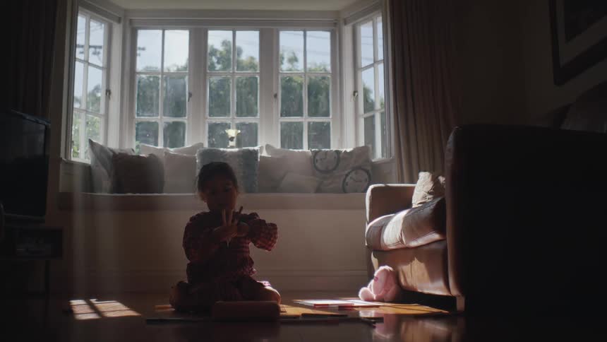 Little girl in living room holding colored pencils