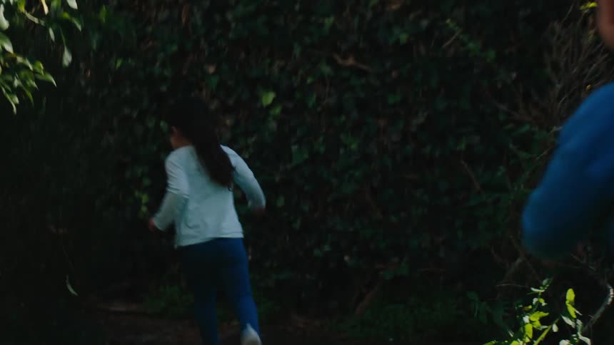 Girl and boy running through the grassy yard