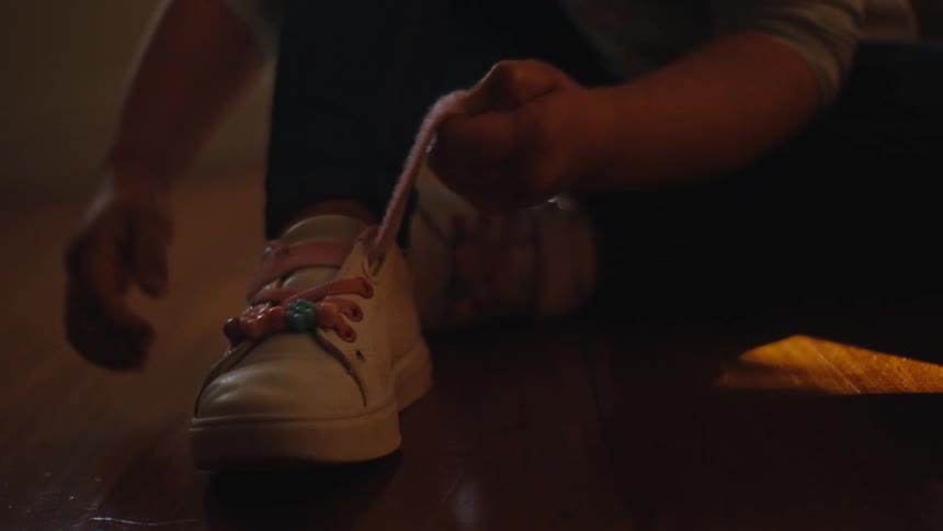 Closeup of a little girls foot finishing tying her shoes and standing up