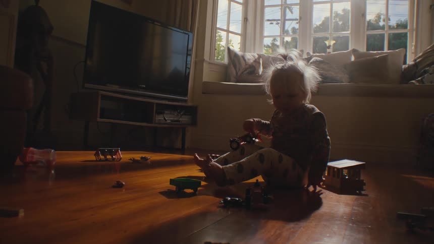Little child sitting in living room and playing with toys