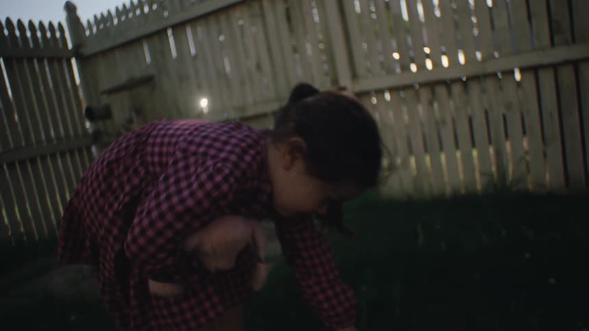 A child runs through the yard carrying a stuffed animal