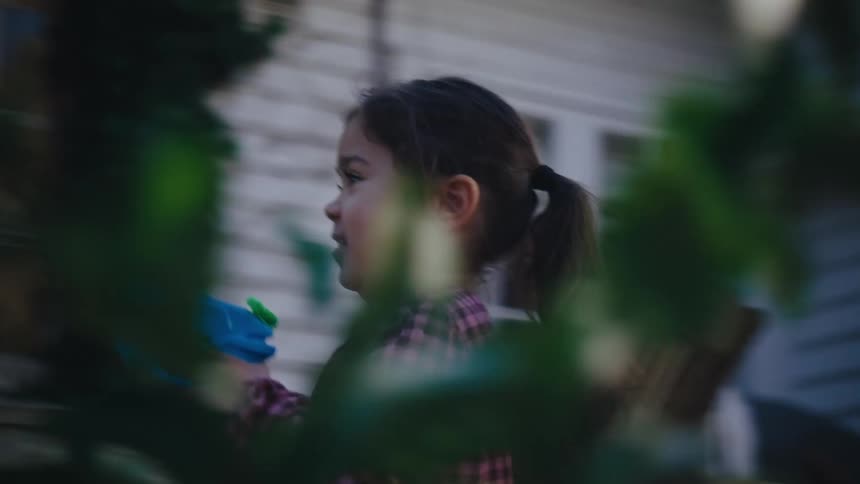 Little girl running in the backyard holding a toy gun